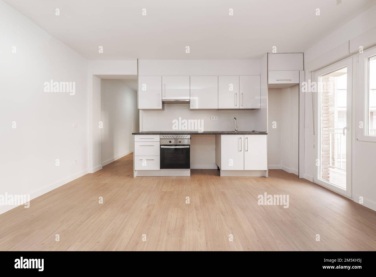 Newly furnished kitchen in an empty apartment with wooden floors, exit ...