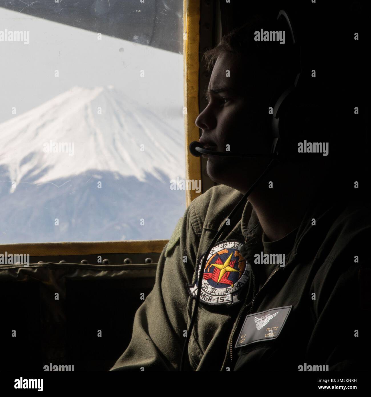 U.S. Marine Corps Sgt. Gabriel Pletz, a loadmaster with Marine Aerial Refueler Transport Squadron (VMGR) 152 observes the terrain from a KC-130J Super Hercules near Mt. Fuji, Japan, March 23, 2022. Marines with VMGR-152 supported Marines with Marine Fighter Attack Squadron 121 during a training flight simulating close air support at Camp Fuji, Japan. Marine Corps aviation routinely conducts training throughout the region to remain combat-ready in support of a free and open Indo-Pacific and to demonstrate our commitment to the Treaty of Mutual Cooperation and Security between the U.S. and Japan Stock Photo
