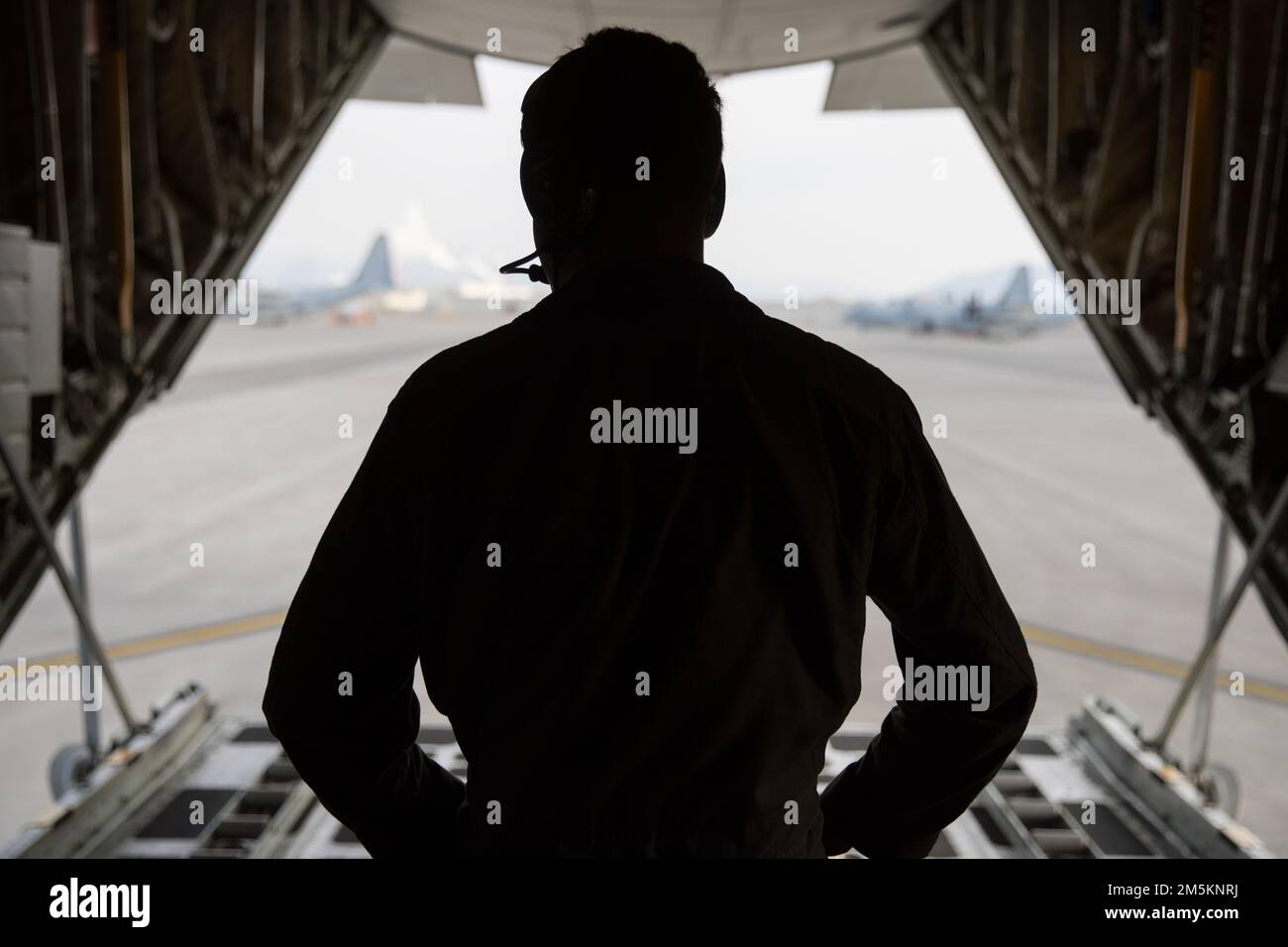U.S. Marine Corps Sgt. Calvin Shirey, a loadmaster with Marine Aerial Refueler Transport Squadron (VMGR) 152 stands on the ramp of a KC-130J Super Hercules at Marine Corps Air Station Iwakuni, Japan, March 23, 2022. Marines with VMGR-152 supported Marines with Marine Fighter Attack Squadron 121 during a training flight simulating close air support at Camp Fuji, Japan. Marine Corps aviation routinely conducts training throughout the region to remain combat-ready in support of a free and open Indo-Pacific and to demonstrate our commitment to the Treaty of Mutual Cooperation and Security between Stock Photo