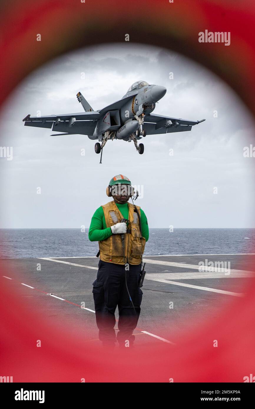 Aviation Boatswain's Mate (Equipment) 1st Class Gabriel Cooper, from Stone Mountain, Georgia, assigned to USS Gerald R. Ford's (CVN 78) air department, stands watch as the arresting gear officer as an F/A-18F Super Hornet attached to the "Blacklions" of Strike Fighter Squadron (VFA) 213 approaches the flight deck for landing during flight operations, March 23, 2022. Ford is underway in the Atlantic Ocean conducting flight deck certification and air wing carrier qualifications as part of the ship’s tailored basic phase prior operational deployment. Stock Photo