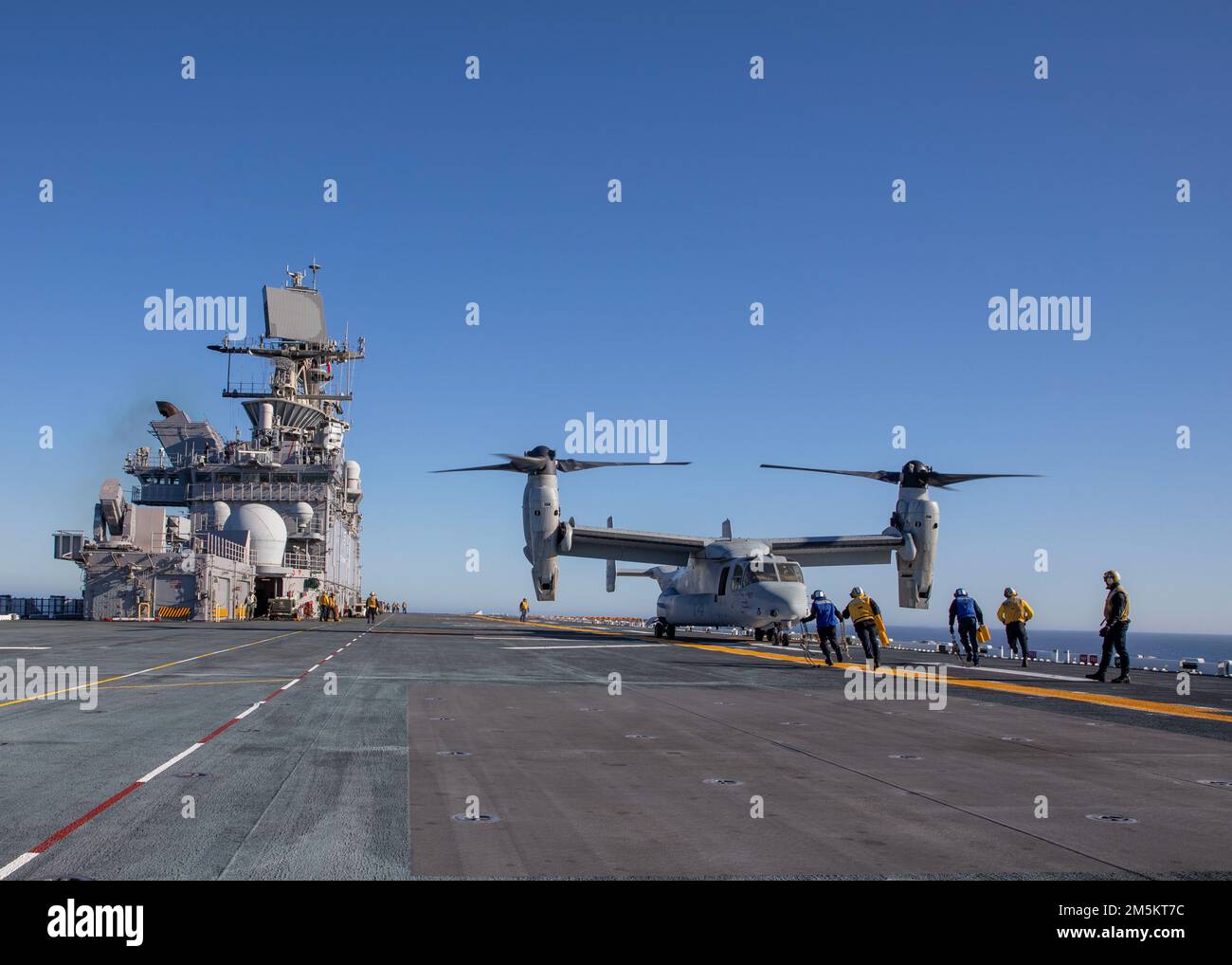 220323-N-IV962-1035    PACIFIC OCEAN (March 23, 2022) – Sailors depart the rotor arc of an MV-22 Osprey, assigned to Marine Medium Tiltrotor Squadron (VMM) 362, aboard amphibious assault ship USS Makin Island (LHD 8), March 23. Makin Island is underway conducting routine operations in U.S. 3rd Fleet. Stock Photo