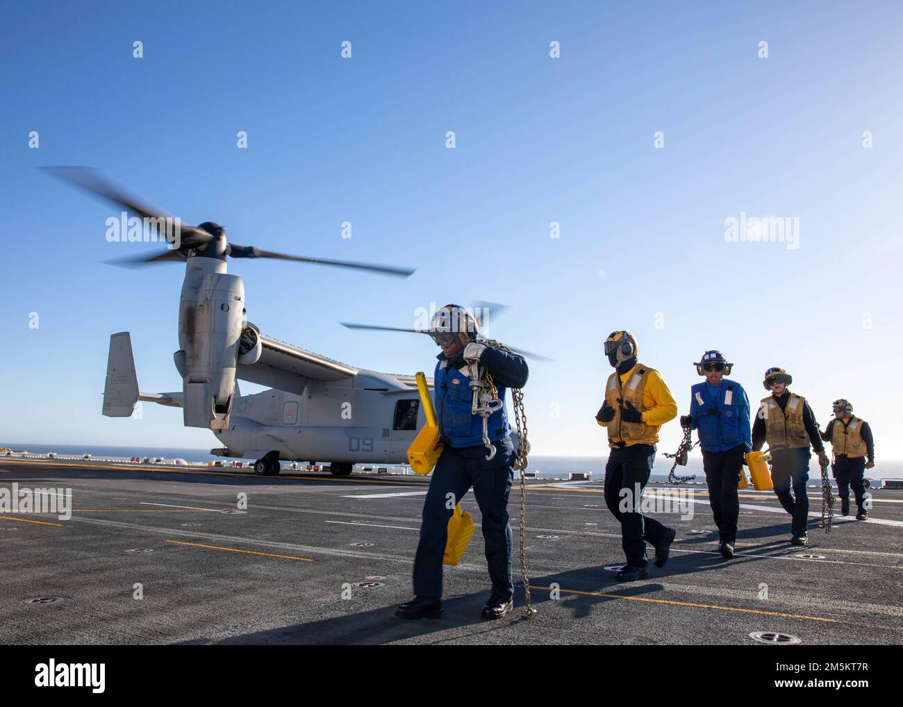 220323-N-IV962-1282    PACIFIC OCEAN (March 23, 2022) – Sailors depart the rotor arc of an MV-22 Osprey, assigned to Marine Medium Tiltrotor Squadron (VMM) 362, aboard amphibious assault ship USS Makin Island (LHD 8), March 23. Makin Island is underway conducting routine operations in U.S. 3rd Fleet. Stock Photo