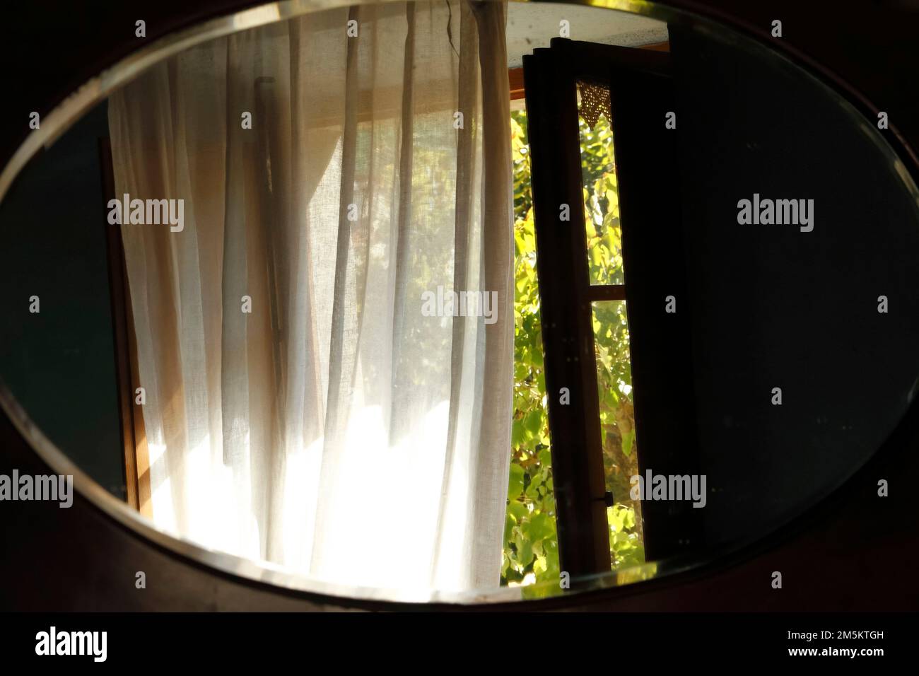 Reflection of window and white tranparent curtain  in oval mirror of a tuscanian house,Tuscany, Italy Stock Photo