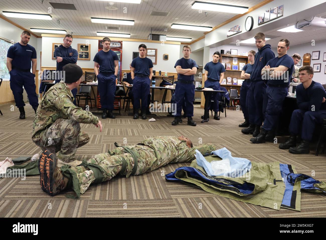 A special forces medical sergeant with 2nd Battalion, 1st Special Forces Group (Airborne) demonstrates to Coast Guardsmen at the United States Coast Guard Station Cape Disappointment how to secure a casualty for movement, March 23, 2022. The Green Beret provided training covering multiple aspects of tactical combat casualty care, providing valuable personal experience and techniques he used across his time in service. Stock Photo