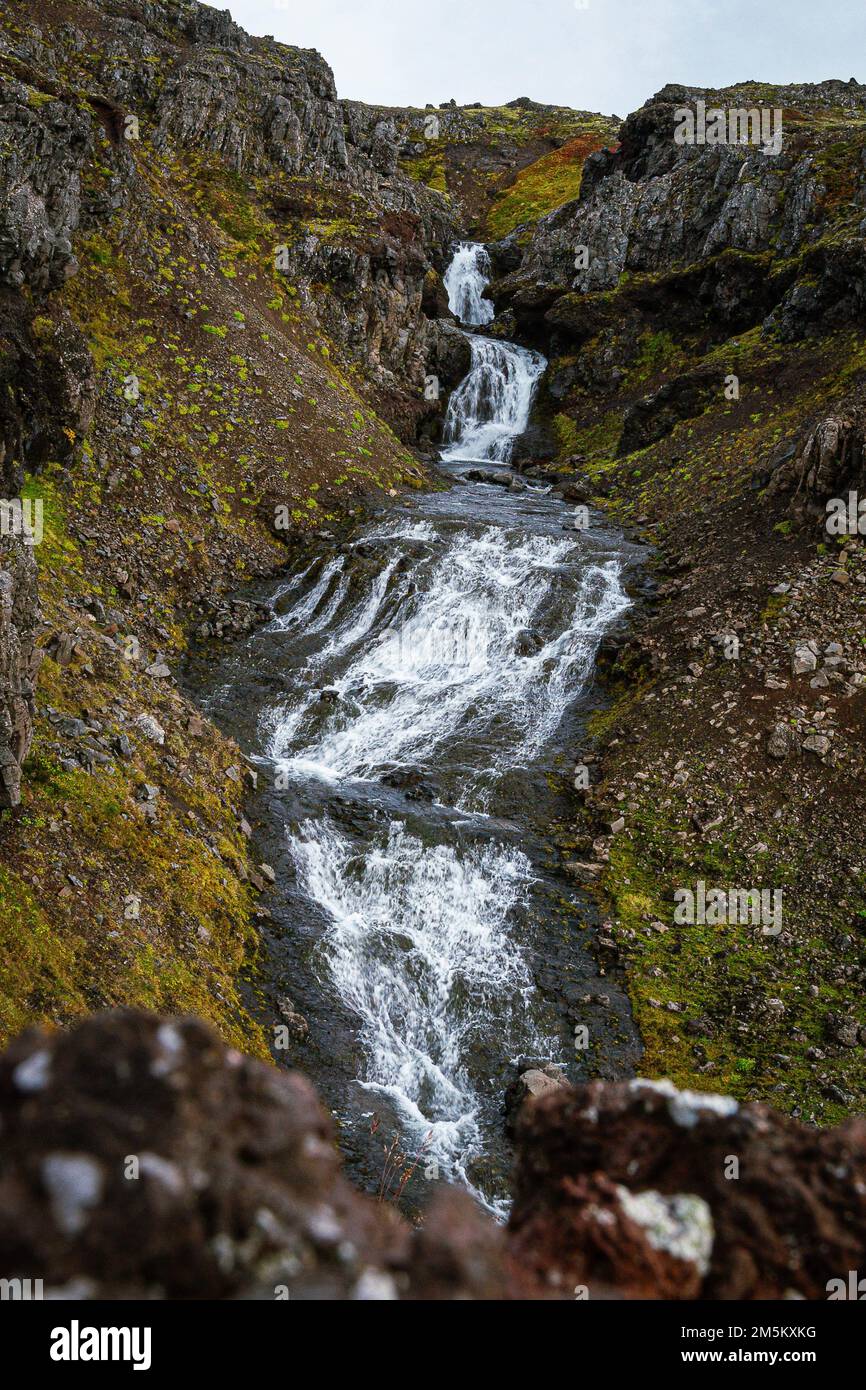 A vertical shot of a waterfall flowing to a rocky stream Stock Photo ...