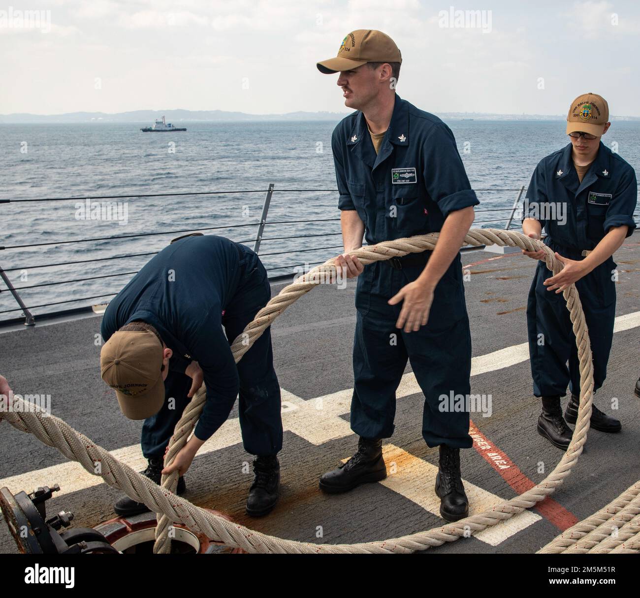 OKINAWA, Japan (March 24, 2022) Sailors pass a line below deck aboard Arleigh Burke-class guided-missile destroyer USS Ralph Johnson (DDG 114). Ralph Johnson is assigned to Task Force 71/Destroyer Squadron (DESRON) 15, the Navy’s largest forward-deployed DESRON and the U.S. 7th fleet’s principal surface force. Stock Photo
