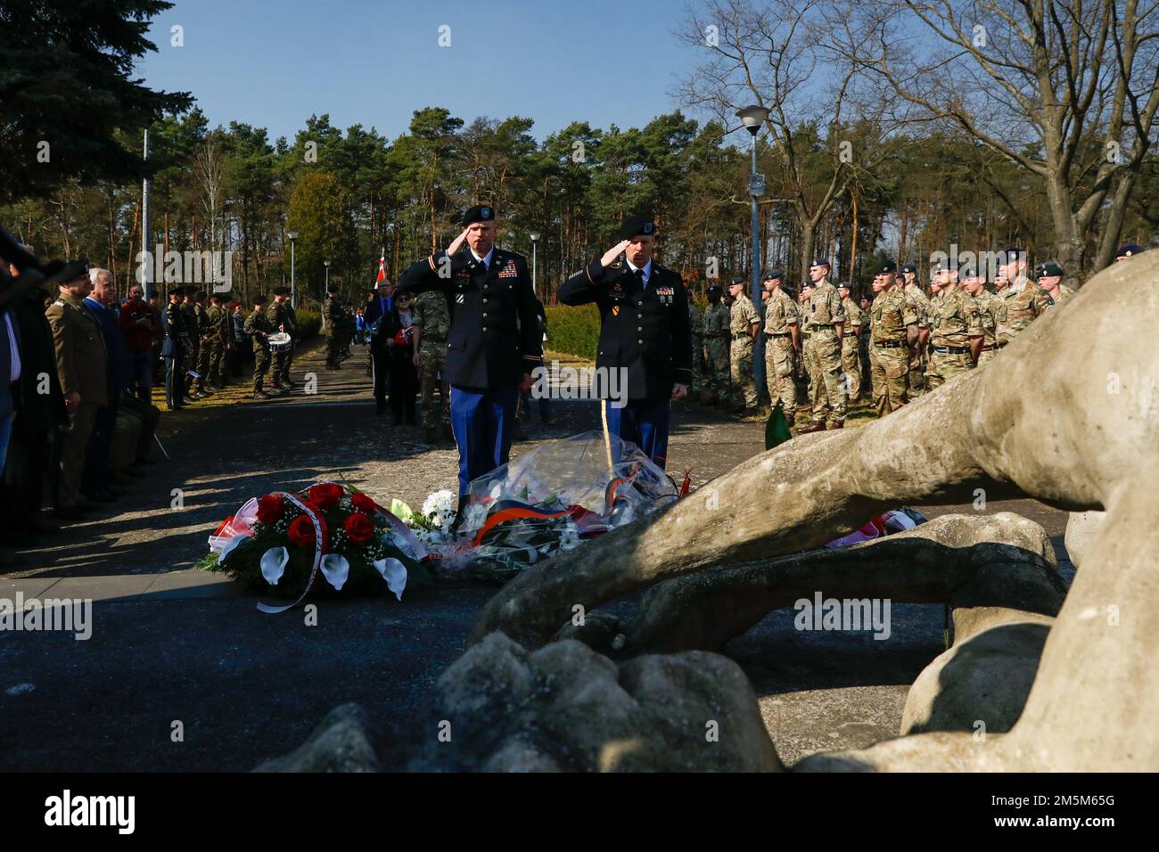U.S. Army Lt. Col. Richard Jones, commander of the 101st Brigade Support Battalion, 1st Armored Brigade Combat Team, 1st Infantry Division and U.S. Army 1st Sgt. Glenn Cook, assigned to the 101 BSB, 1ABCT, 1ID render a salute to the memorial at Stalag Luft III during a commemoration event at Zagan, Poland, March 24, 2022. Service members of various nations participated in the commemoration of what is known as the 'Great Escape,' an escape attempt orchestrated by British Royal Air Force airmen from a German prisoner of war camp in Zagan during World War II and ended in the execution of 50 recap Stock Photo