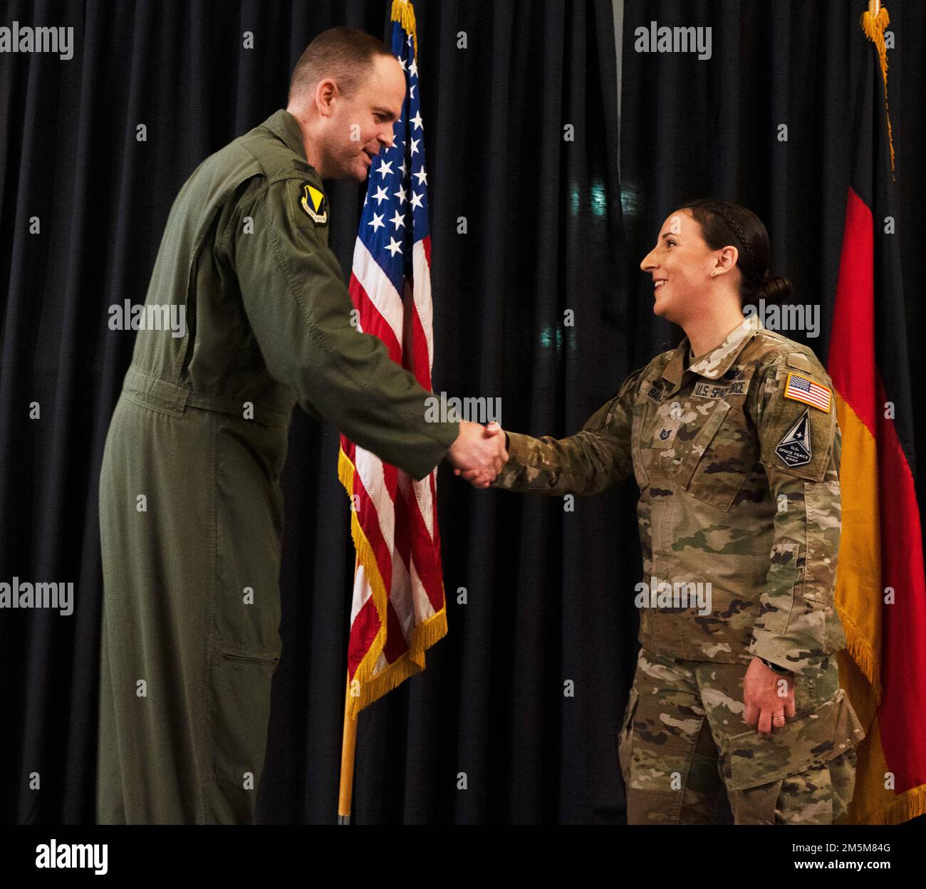 U.S. Space Force Tech. Sgt. Hollie Baire, non-commissioned officer in charge of the 86th Communications Squadron non-commissioned officer in charge of the Technical Control Facility receives a coin from U.S. Air Force Col. Denny Davies, 86th Airlift Wing Vice Commander at an all call at Ramstein Air Base, Germany, March 24 2022. Baire was awarded the title of Airlifter of the Week due to her part in facilitating the installation of $750,000 of new Defense Information Systems. Stock Photo