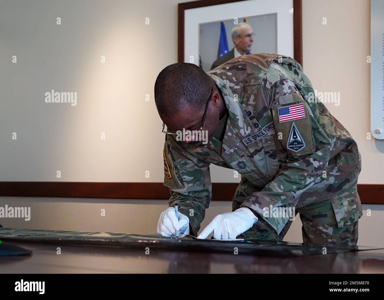 U.S. Space Force CMSgt. Willie H. Frazier II, Senior Enlisted Leader, Space Systems Command (SSC), signs a thermal space blanket, during the “Space Blanket” signing ceremony, at Los Angeles Air Force Base, SSC, in El Segundo, Calif., Mar. 24, 2022.  The space blanket will protect sensitive components inside the sixth Space Based Infrared System Geosynchronous Earth Orbit (SBIRS GEO-6) satellite from extreme temperature changes during its life-span around Earth’s orbit. (Photo by: Walter Talens, SSC/PA) Stock Photo