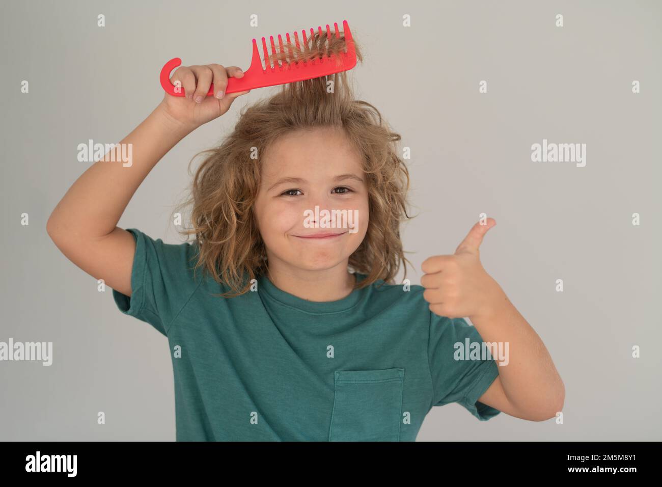 Boy brushes his hair. Cute child with comb. Blonde kid combs unruly