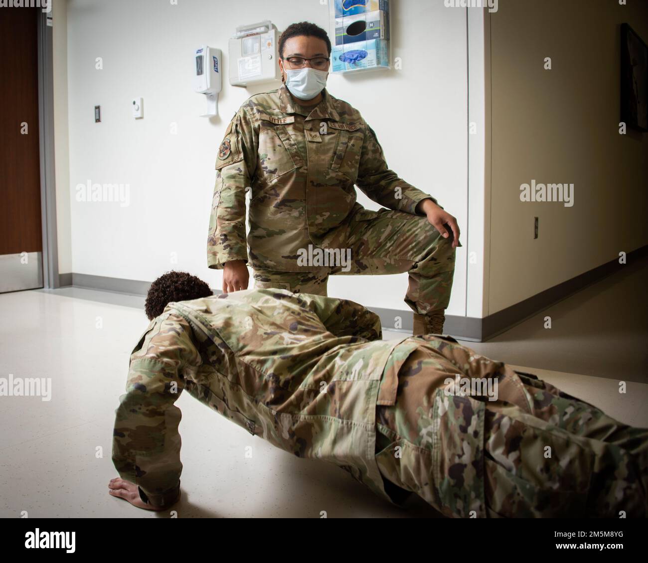 U.S. Air Force Staff Sgt. Aleah Little, occupational therapy assistant, instructs a patient on alternate wrist placement for doing push-ups during injury recovery at the Wilford Hall Ambulatory Surgical Center, Lackland Air Force Base, Texas, March 24, 2022. Occupational Therapy’s unique role emphasizes enhancing individual functional performance in various life roles, such as Airman, worker, parent, student and retiree. Stock Photo