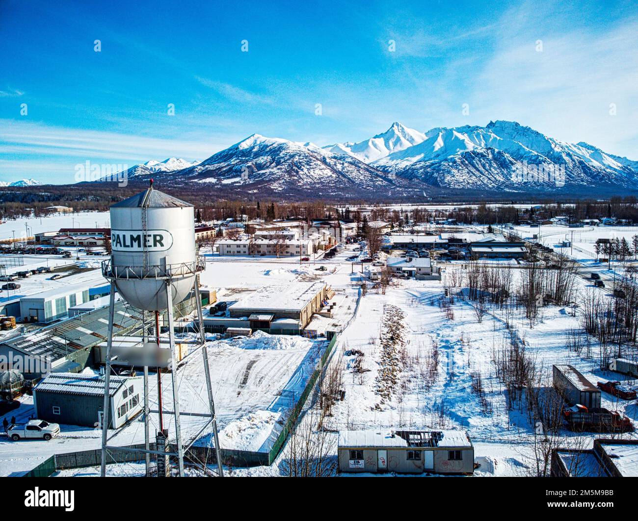An aerial shot of the water tower of Palmer and industrial buildings covered in snow, Alaska Stock Photo