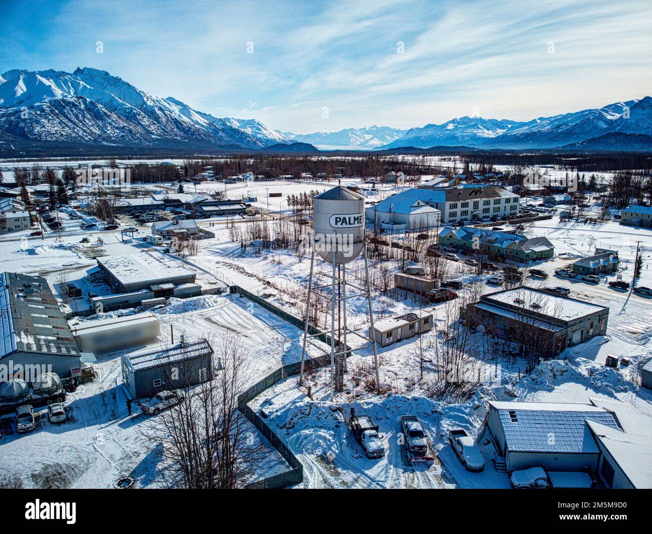 An aerial winter view of the city of Palmer covered in snow and surrounded by rocky mountains Stock Photo