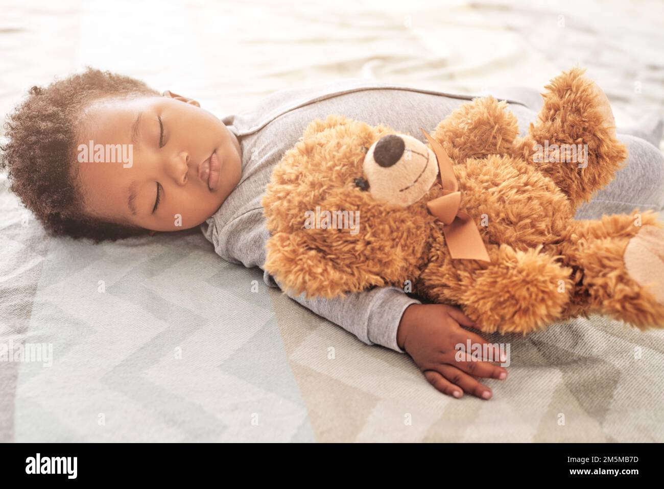 With teddy close by he has the softest sweetest dreams. a little baby boy sleeping on a bed with a teddy bear. Stock Photo
