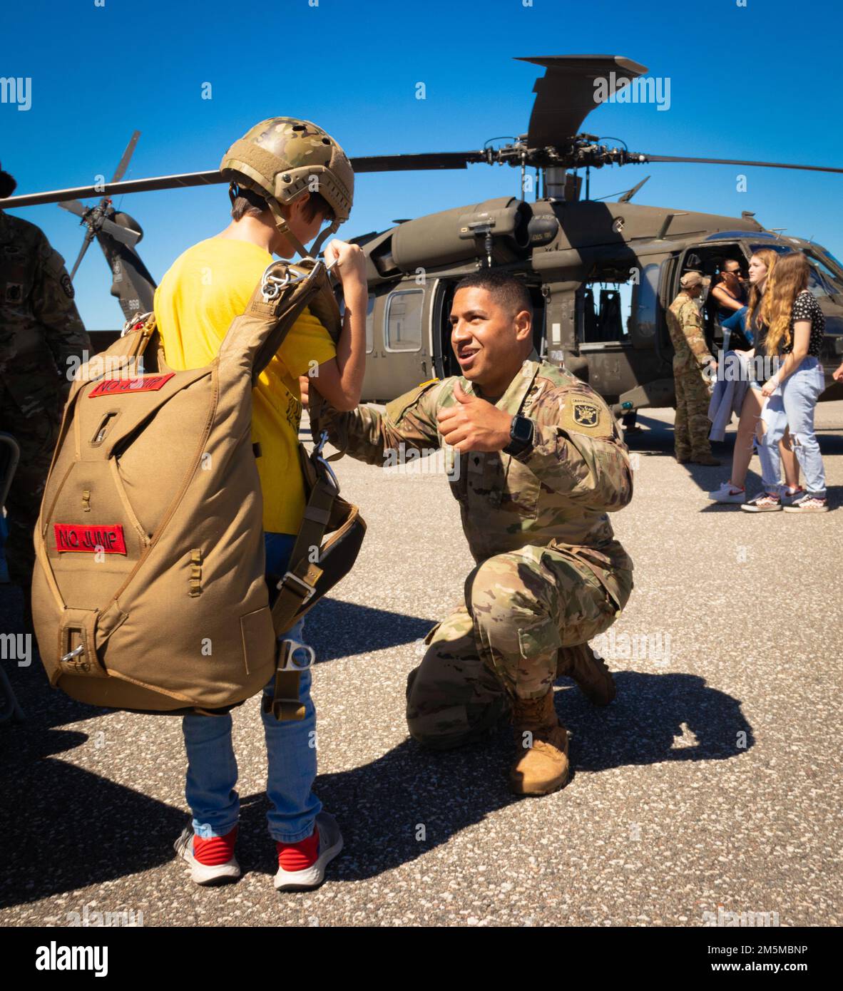 U.S. Army Spc. Nathaniel L. Petrini, a parachute rigger assigned to C Company, Support Battalion, 1st Special Warfare Training Group, helps a boy put on a parachute during the Tampa Bay Airfest hosted at MacDill Air Force Base, Florida, March 26, 2022. Petrini, a native of the Islando of Hawaii, was one of dozens of Soldiers who helped set up and operate the Airfest’s Army Village. The Army Village featured a myriad of modern and historical Army vehicles, helicopters and airborne equipment. The static and interactive displays attracted thousands of visitors and offered hundreds of opportunitie Stock Photo