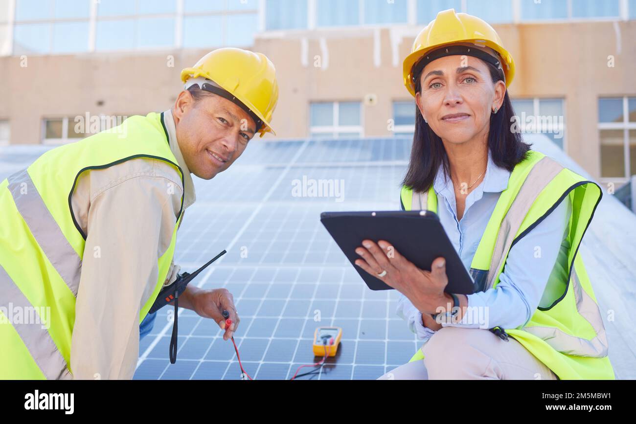 Tablet, solar energy or engineering team working solar panels or technology on rooftop for renewable energy. Teamwork, portrait or construction Stock Photo