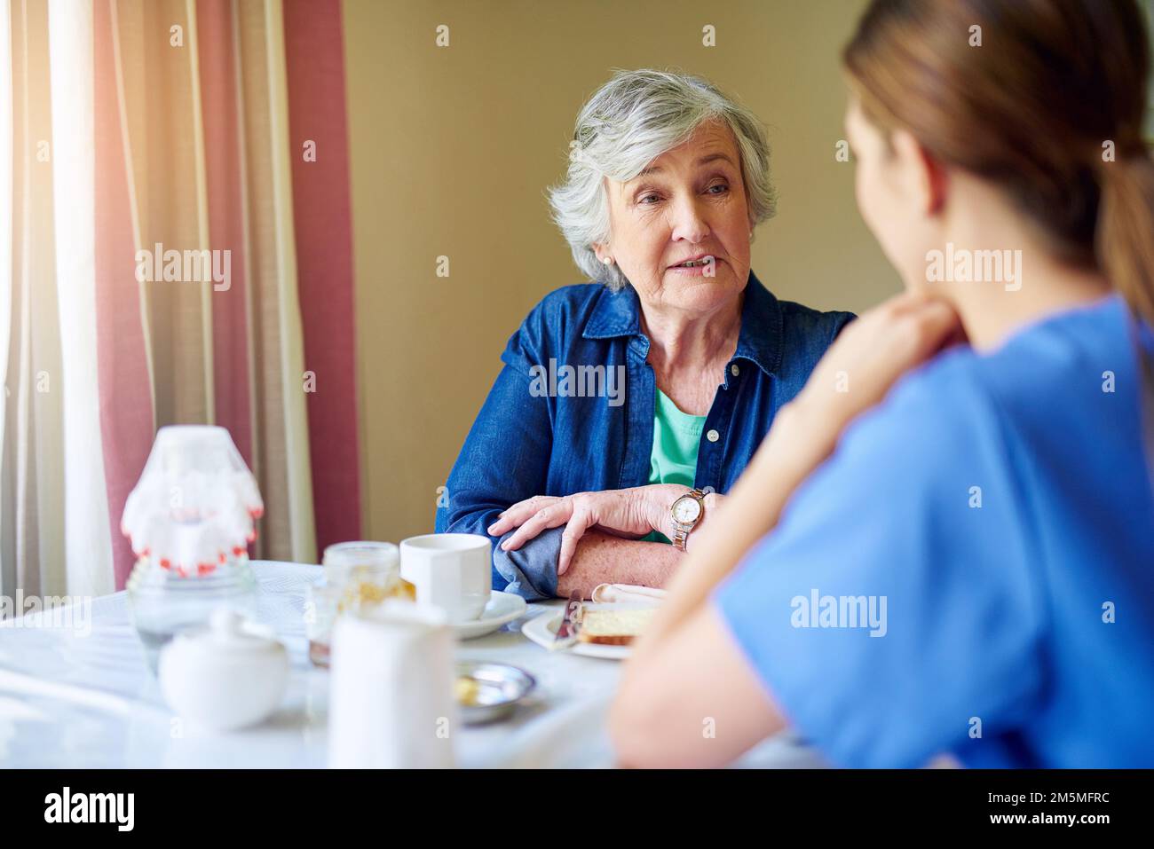 Having a little chat over breakfast. a resident and a nurse at a retirement home. Stock Photo