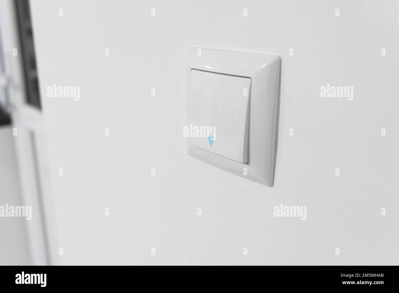 Light switch. White plastic mechanical switch installed on a white wall. Turn on and off. White
