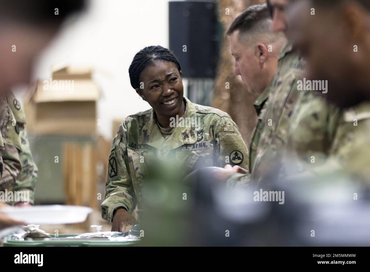 Col. Fenicia L. Jackson, chief of staff, 3rd Expeditionary Sustainment Command, shares a laugh with Col. Sean P. Davis, deputy commanding officer, 1st Theater Sustainment Command, while serving food to Soldiers during a tactical dining-in at Camp Arifjan, Kuwait, Mar. 26, 2022. Brig. Gen. Lance G. Curtis, commanding general, 3rd ESC, hosted the event to uphold U.S. military customs and traditions, foster camaraderie and esprit de corps, and acknowledge the unit’s accomplishments during its deployment in support of 1st TSC. Stock Photo