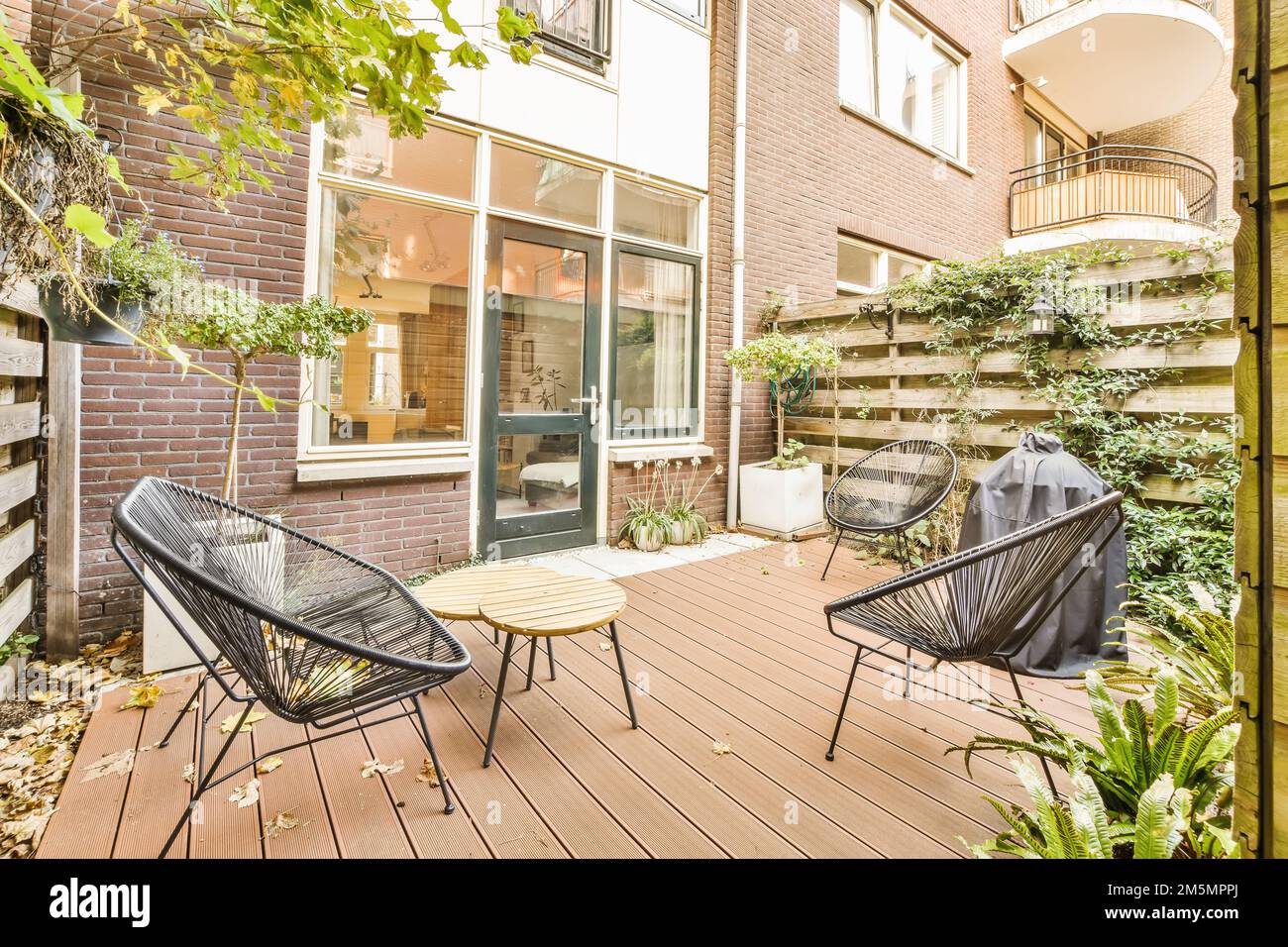 a patio with two chairs and a table on the deck, in front of a brick ...