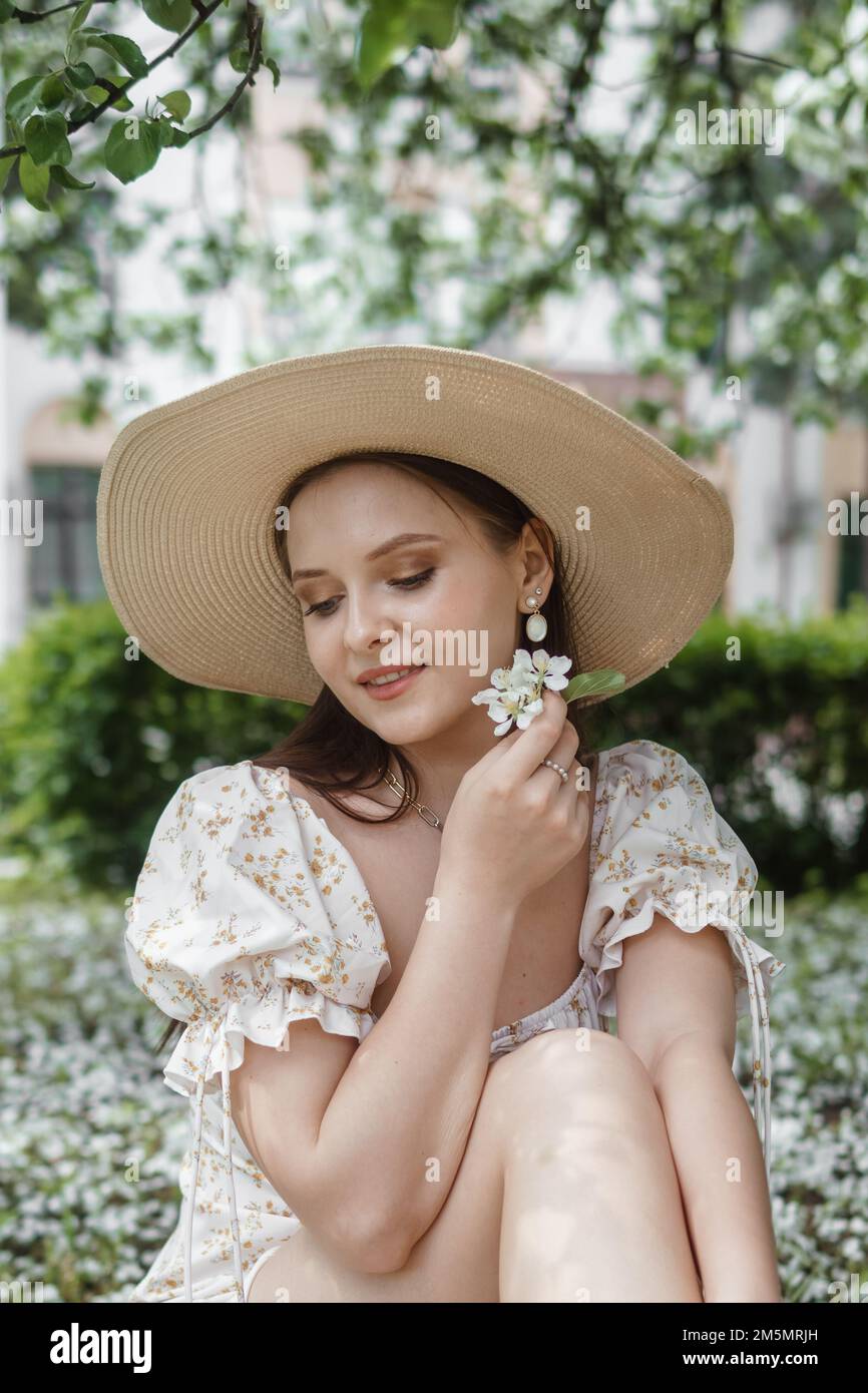 An attractive long-haired woman walks in the spring in the park of blooming apple trees. Spring portrait of a woman Stock Photo