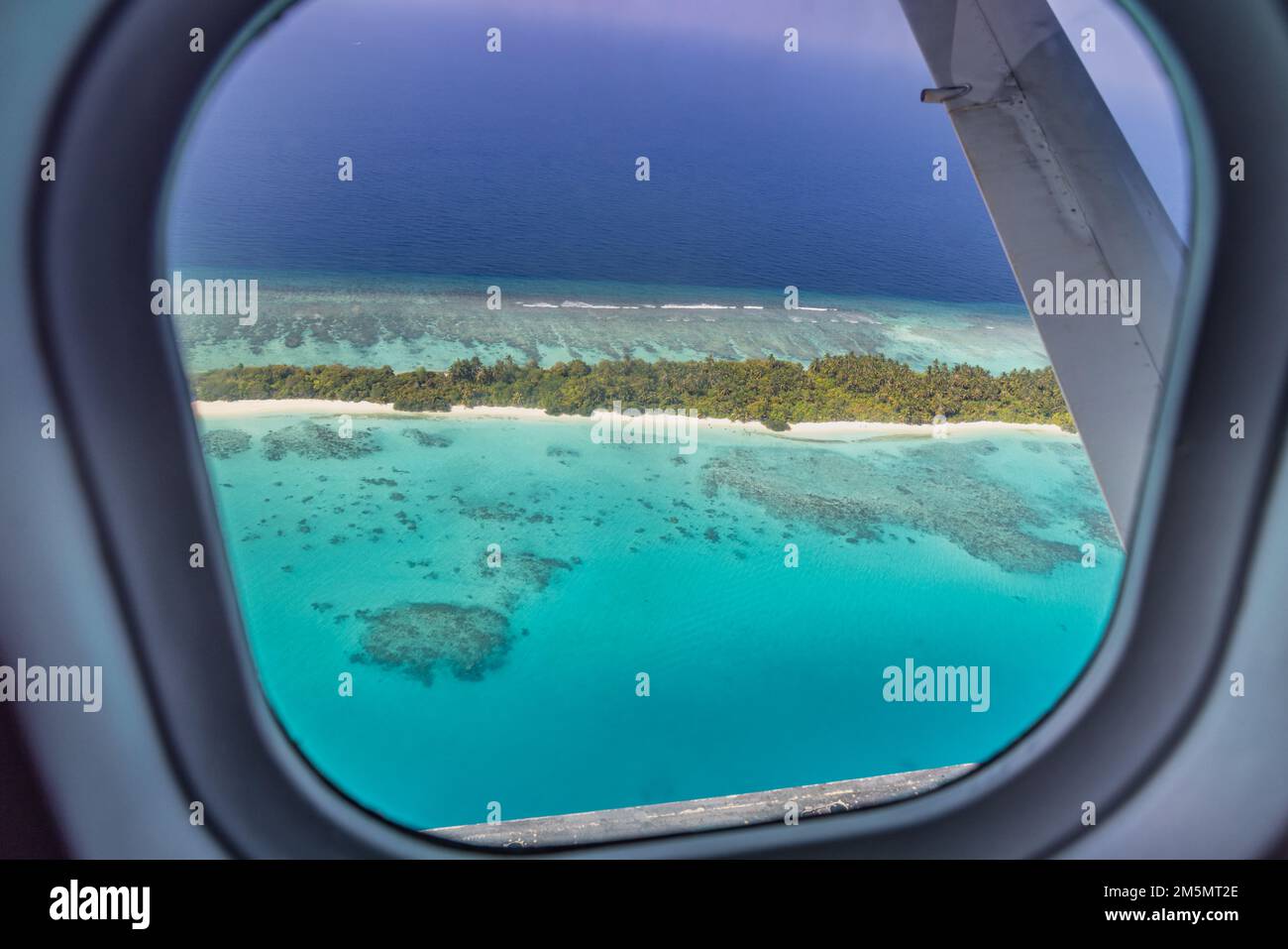 Airplane window with beautiful Maldives island view. Luxury summer holiday travel tourism background, view from airplane window. Atolls islands Stock Photo