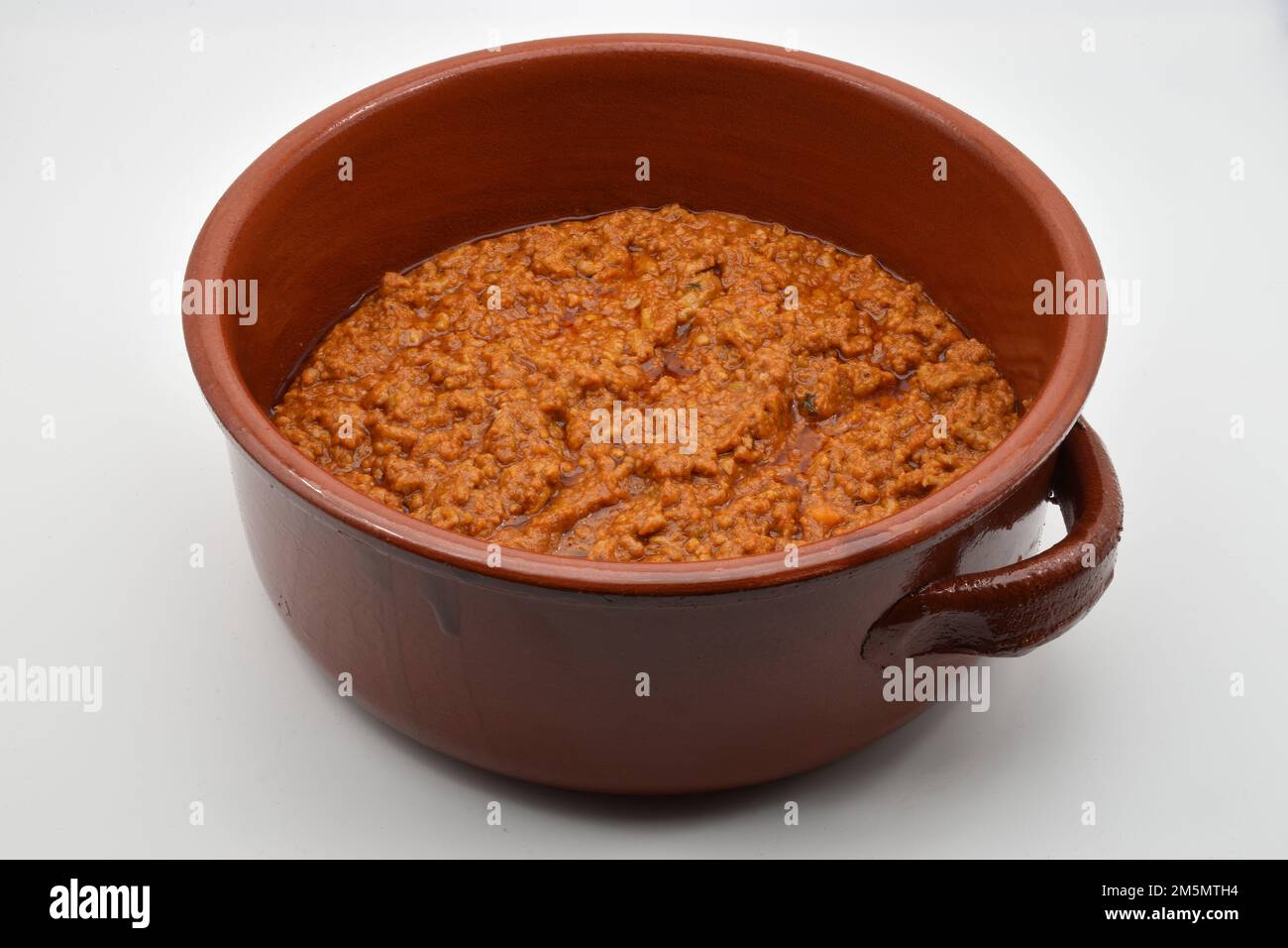 Italian bolognese ragu in a crock pot, isolated on white background