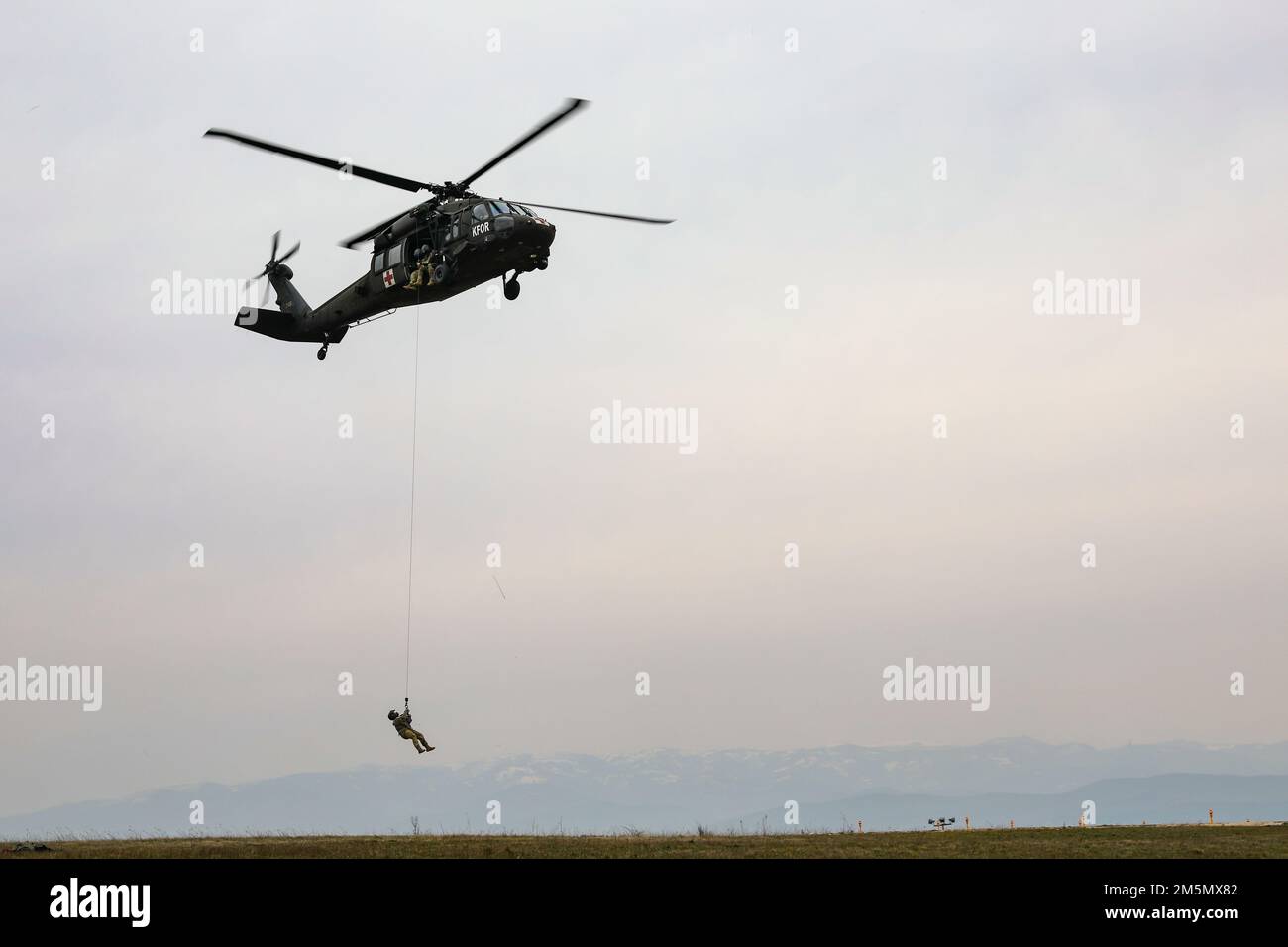 U.S. Army Soldiers assigned to Detachment 2, Charlie Company, 1st Battalion, 169th Aviation Regiment, Virginia National Guard, conduct high-performance rescue hoist, or HPU, training at Camp Bondsteel, Kosovo, March 28, 2022. The HPU device allows medical evacuation teams to safely extract individuals from areas where landing an aircraft isn’t safe or possible. Stock Photo