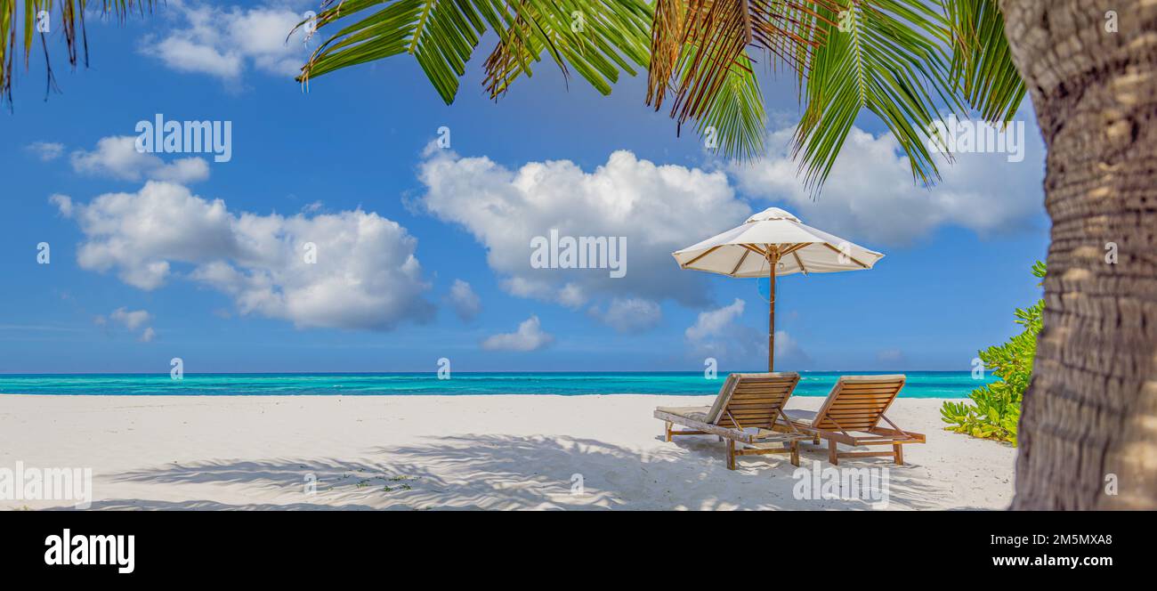 Amazing vacation panorama on summer island beach. Two chairs with palm leaves and umbrella, close seaside, horizon. Exotic landscape tropical paradise Stock Photo