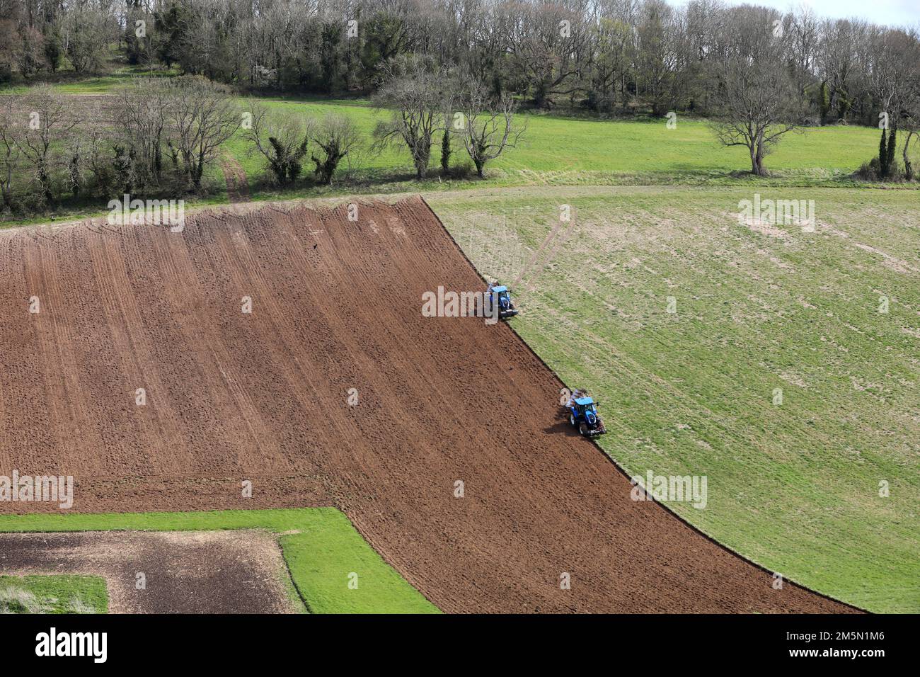 Two tractors pictured farming Goodwood land in Chichester, West Sussex