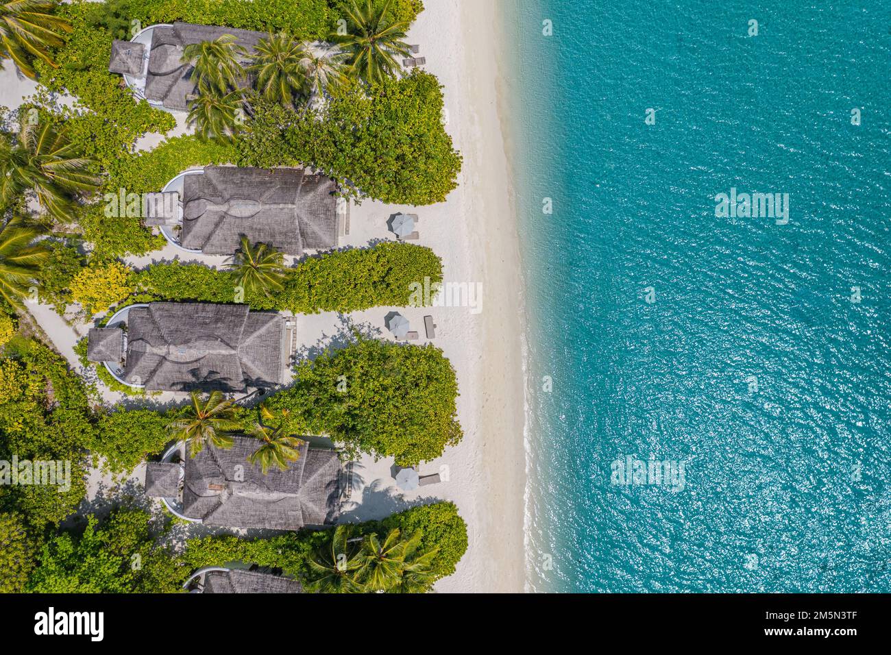 Beautiful atoll and island in Maldives from aerial view. Tranquil tropical landscape and seascape with palm trees on white sandy beach, amazing nature Stock Photo