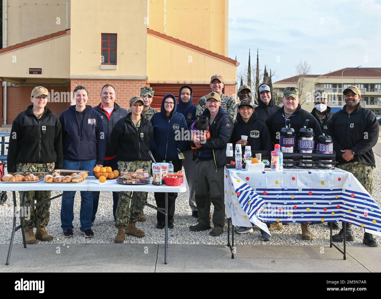 220329-N-GK686-1131 NAVAL AIR STATION SIGONELLA, Italy (Mar. 29, 2022)—U.S. Navy chiefs and USO employees pose for a group photo after handing out breakfast to service members in honor of the upcoming Chief’s Birthday on Naval Air Station Sigonella, Mar. 29, 2022. NAS Sigonella’s strategic location enables U.S., allied, and partner nation forces to deploy and respond as required, ensuring security and stability in Europe, Africa and Central Command. Stock Photo