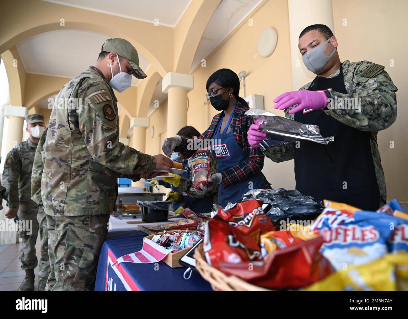 220329-N-OX321-1037 NAVAL AIR STATION SIGONELLA, Italy (March 29, 2022) – Senior Chief Intelligence Specialist Robert Holder from St. Thomas, Virgin Islands, and U.S. Army Corporal Asia Bradley from Sumter, N.C., serve lunch at the USO Troop Lunch to help raise awareness for the Chief’s Birthday at Naval Air Station Sigonella on March 29, 2022. NAS Sigonella’s strategic location enables U.S., allied, and partner nation forces to deploy and respond as required, ensuring security and stability in Europe, Africa, and Central Command. Stock Photo