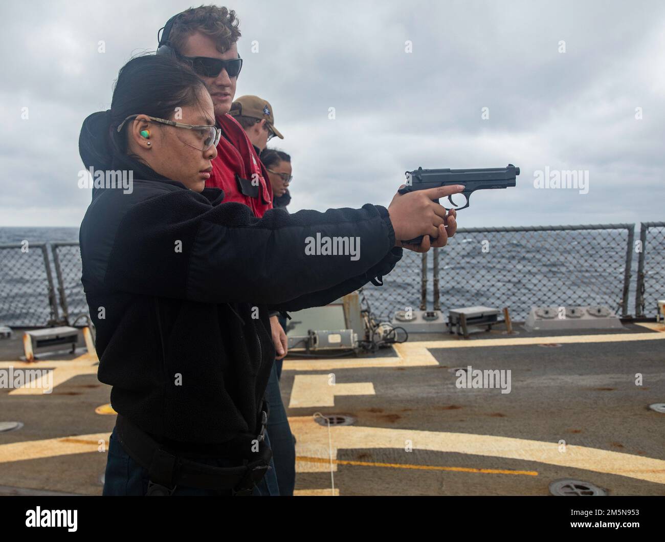 EAST CHINA SEA (March 28,2022) Operations Specialist Seaman Htee Shee, from Laverne, Tennessee, shoots a 9mm pistol during a small-arms live-fire qualification aboard the Arleigh Burke-class guided-missile destroyer USS Ralph Johnson (DDG 114). Ralph Johnson is forward-deployed to the U.S. 7th Fleet area of operations in support of a free and open Indo-Pacific. Stock Photo