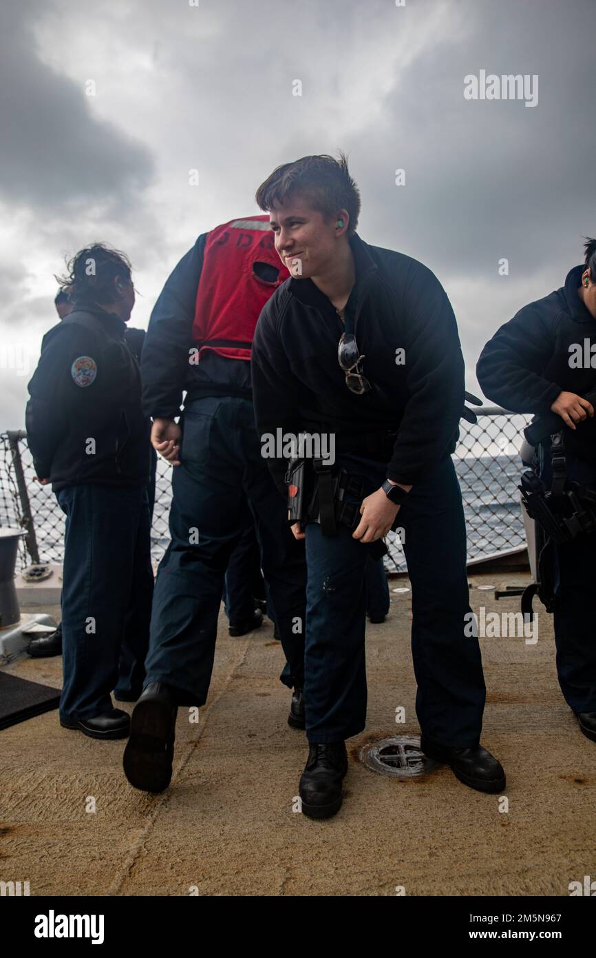 EAST CHINA SEA (March 28,2022) Specialist Seaman Recruit Tiffany Eldridge (left), from Lakeland, Florida, puts on a holster during a small-arms live-fire qualification aboard the Arleigh Burke-class guided-missile destroyer USS Ralph Johnson (DDG 114). Ralph Johnson is forward-deployed to the U.S. 7th Fleet area of operations in support of a free and open Indo-Pacific. Stock Photo