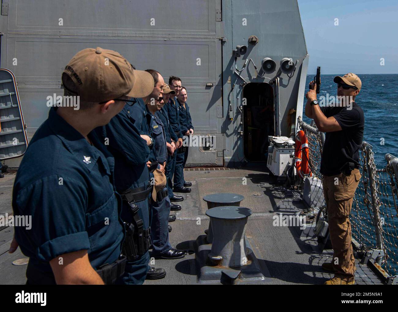 ARABIAN GULF (March 29, 2022) Gunner’s Mate 2nd Class Omar Gutierrez, right, teaches Sailors about M9 pistol familiarization prior to starting a weapons certification aboard the guided-missile destroyer USS Gridley (DDG 101) in the Arabian Gulf, March 29. Gridley is deployed to the U.S. 5th Fleet area of operations to help ensure maritime security and stability in the Middle East Region. Stock Photo