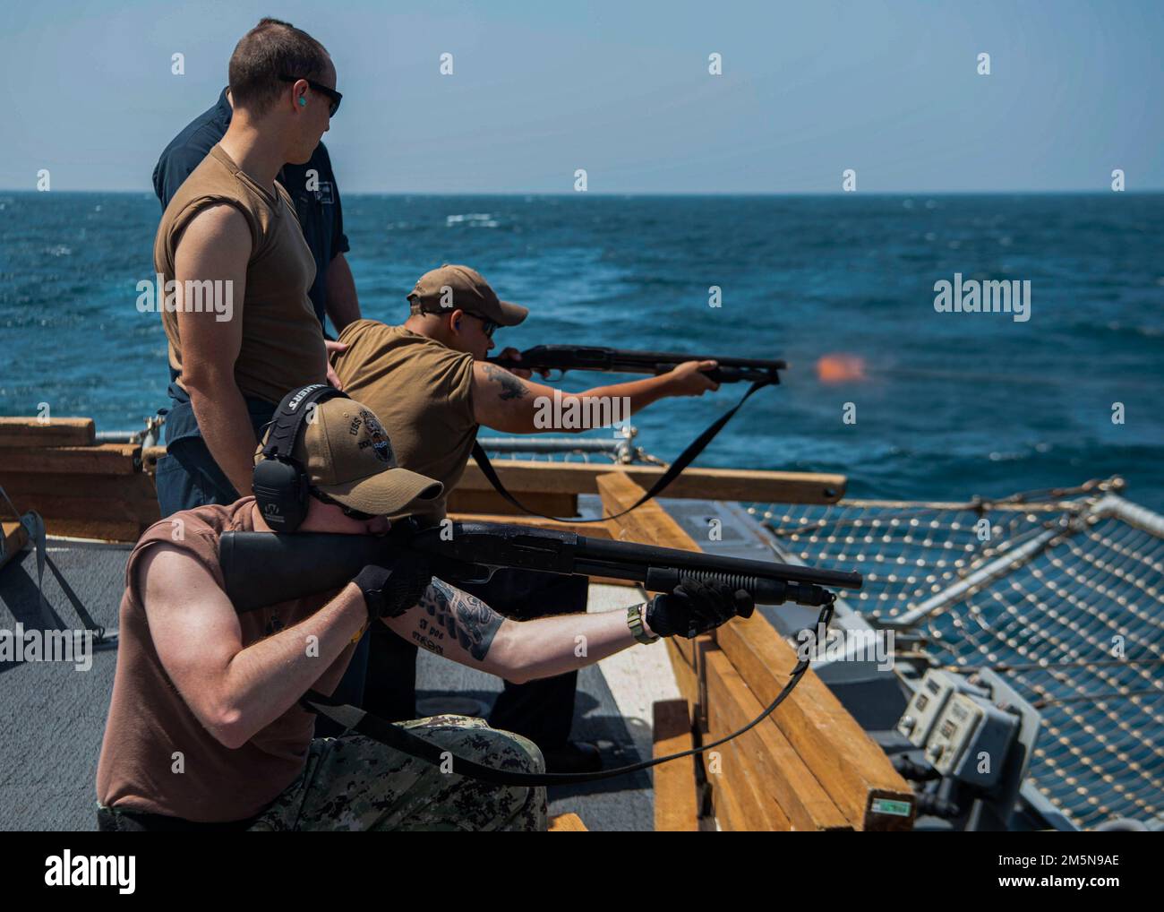 ARABIAN GULF (March 29, 2022) Master-at-Arms 1st Class William Elliott, left, and Boatswain’s Mate 2nd Class Rigoberto Sandoval, middle, fire M500 shotguns during a weapons certification aboard the guided-missile destroyer USS Gridley (DDG 101) in the Arabian Gulf, March 29. Gridley is deployed to the U.S. 5th Fleet area of operations to help ensure maritime security and stability in the Middle East Region. Stock Photo