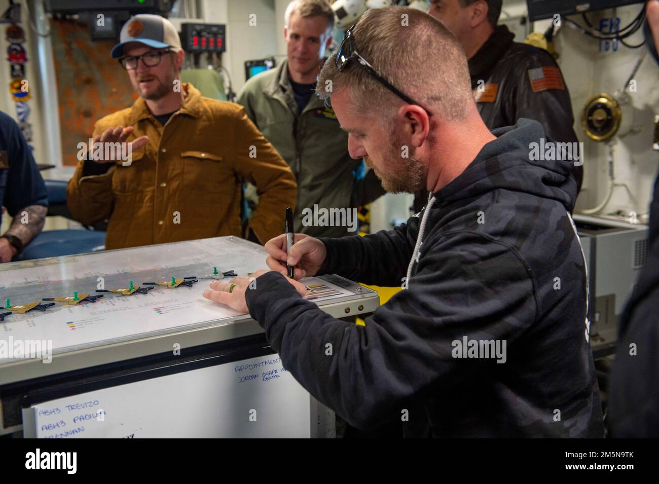 220329-N-OL632-1060 NAVAL STATION NORFOLK (March 29, 2022) NASCAR Xfinity Series driver Justin Allgaier, signs an autograph during a visit to the aircraft carrier USS George H.W. Bush (CVN 77), March 29, 2022. George H.W. Bush provides the national command authority flexible, tailorable war fighting capability as the flagship of the carrier strike group which maintains maritime stability and security in order to ensure access, deter aggression and defend U.S., allied and partner interests. Stock Photo