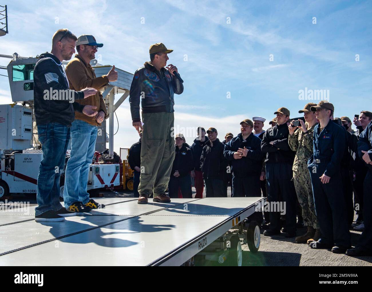 220329-N-OL632-1133 NAVAL STATION NORFOLK (March 29, 2022) Capt. Robert Aguilar, commanding officer of USS George H.W. Bush (CVN 77), addresses the crew with NASCAR Hall of Famer Dale Earnhardt Jr. and NASCAR Xfinity Series driver Justin Allgaier during a visit to the ship, March 29, 2022. George H.W. Bush provides the national command authority flexible, tailorable war fighting capability as the flagship of the carrier strike group which maintains maritime stability and security in order to ensure access, deter aggression and defend U.S., allied and partner interests. Stock Photo
