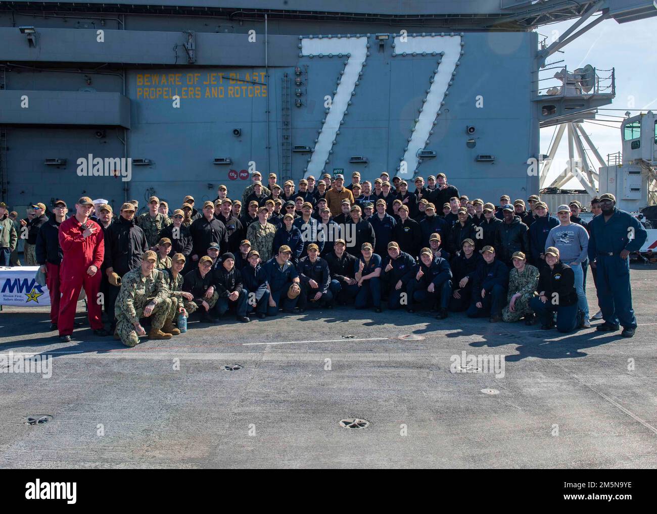 220329-N-OL632-1177 NAVAL STATION NORFOLK (March 29, 2022) NASCAR Hall of Famer Dale Earnhardt Jr. and NASCAR Xfinity Series driver Justin Allgaier take a group photo with Sailors assigned to the aircraft carrier USS George H.W. Bush (CVN 77) during a visit to the ship, March 29, 2022. George H.W. Bush provides the national command authority flexible, tailorable war fighting capability as the flagship of the carrier strike group which maintains maritime stability and security in order to ensure access, deter aggression and defend U.S., allied and partner interests. Stock Photo