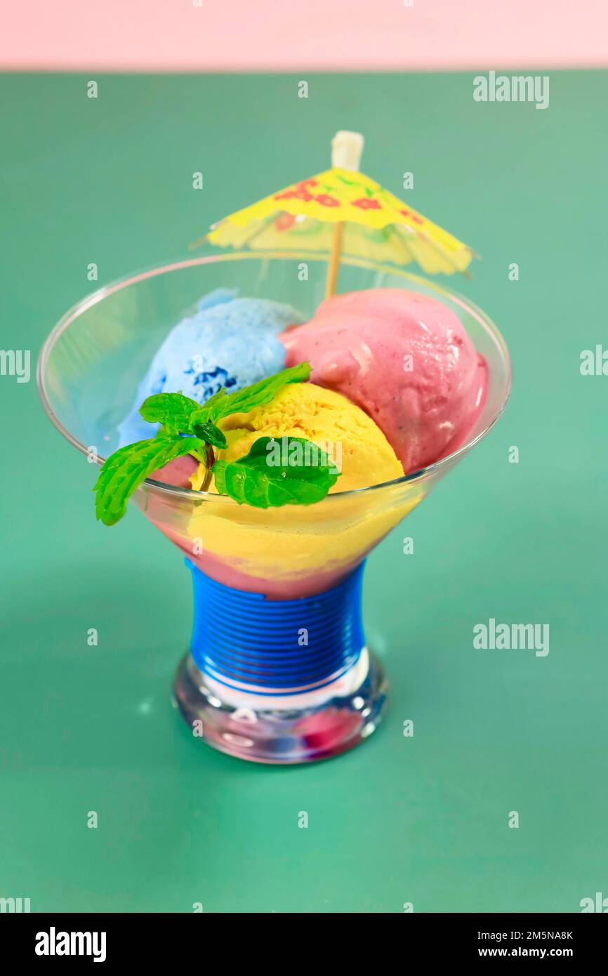 Homemade ice cream in a glass bowl with mint and umbrella, summer