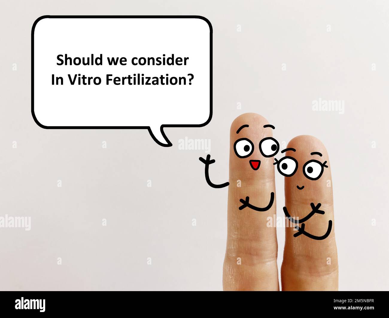 Two fingers are decorated as two person. One of them is asking another if they should consider in vitro fertilisation. Stock Photo