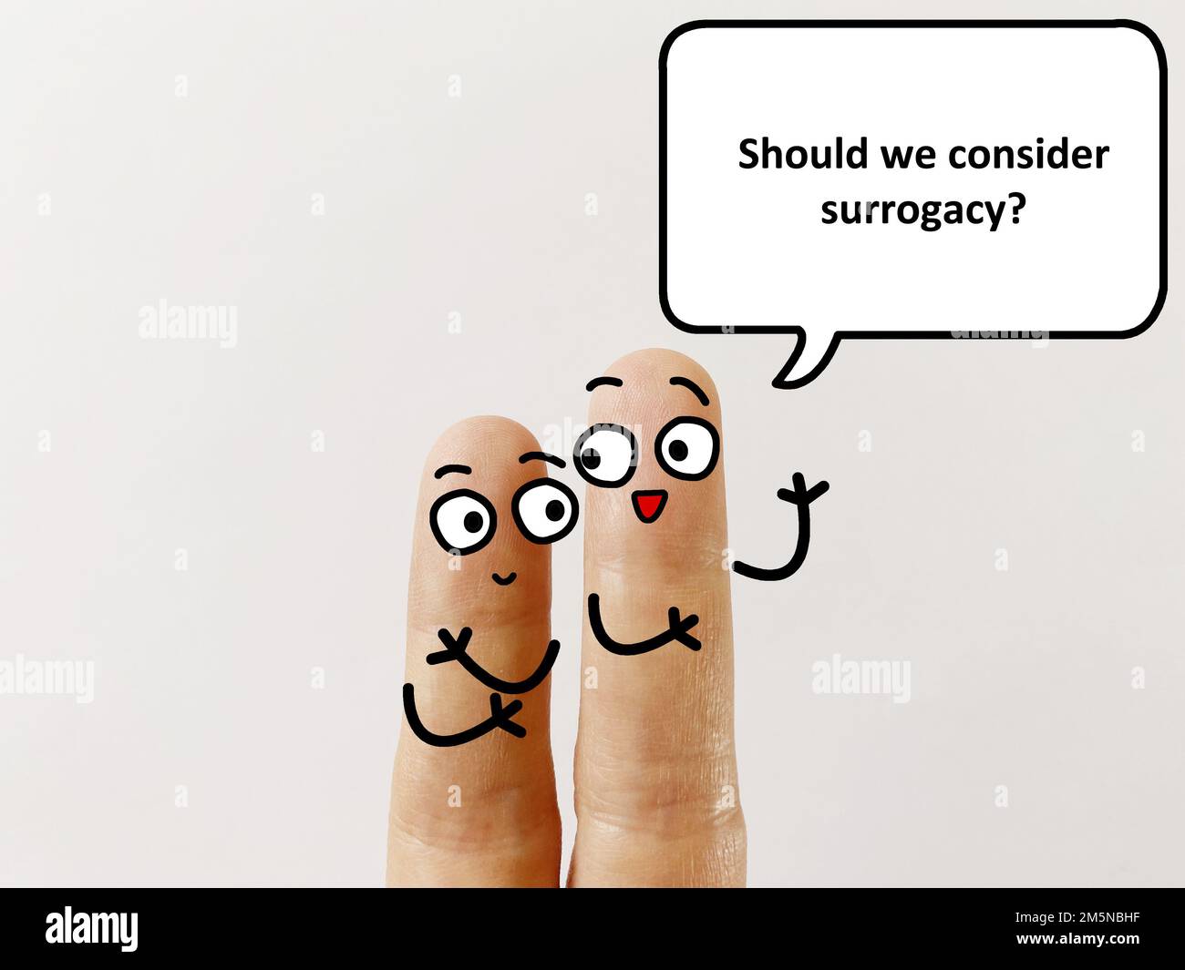 Two fingers are decorated as two person. One of them is asking another if they should consider surrogacy. Stock Photo