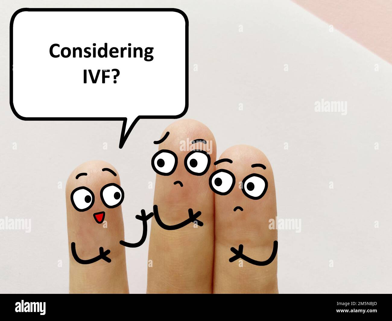 Three fingers are decorated as three person. One of them is asking if they are considering in vitro fertilization. Stock Photo