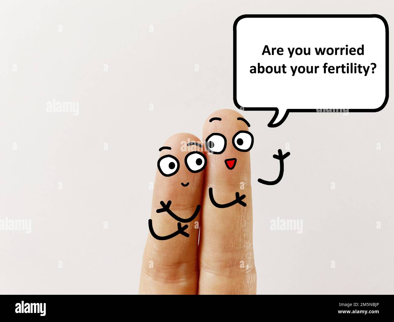 Two fingers are decorated as two person. One of them is asking if she is worried about her fertility. Stock Photo