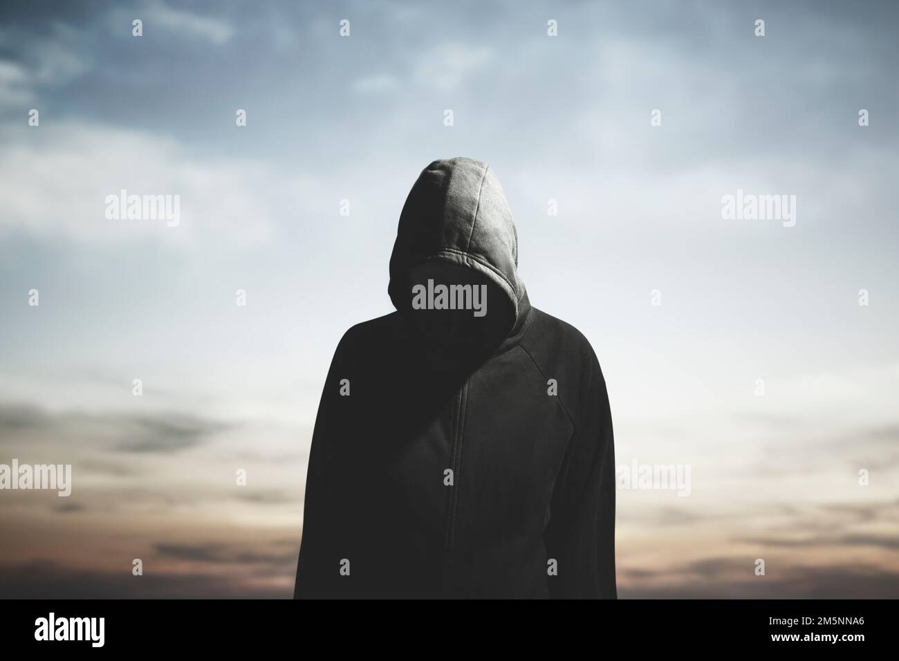 surreal man with hood and obscured face wanders aimlessly Stock Photo