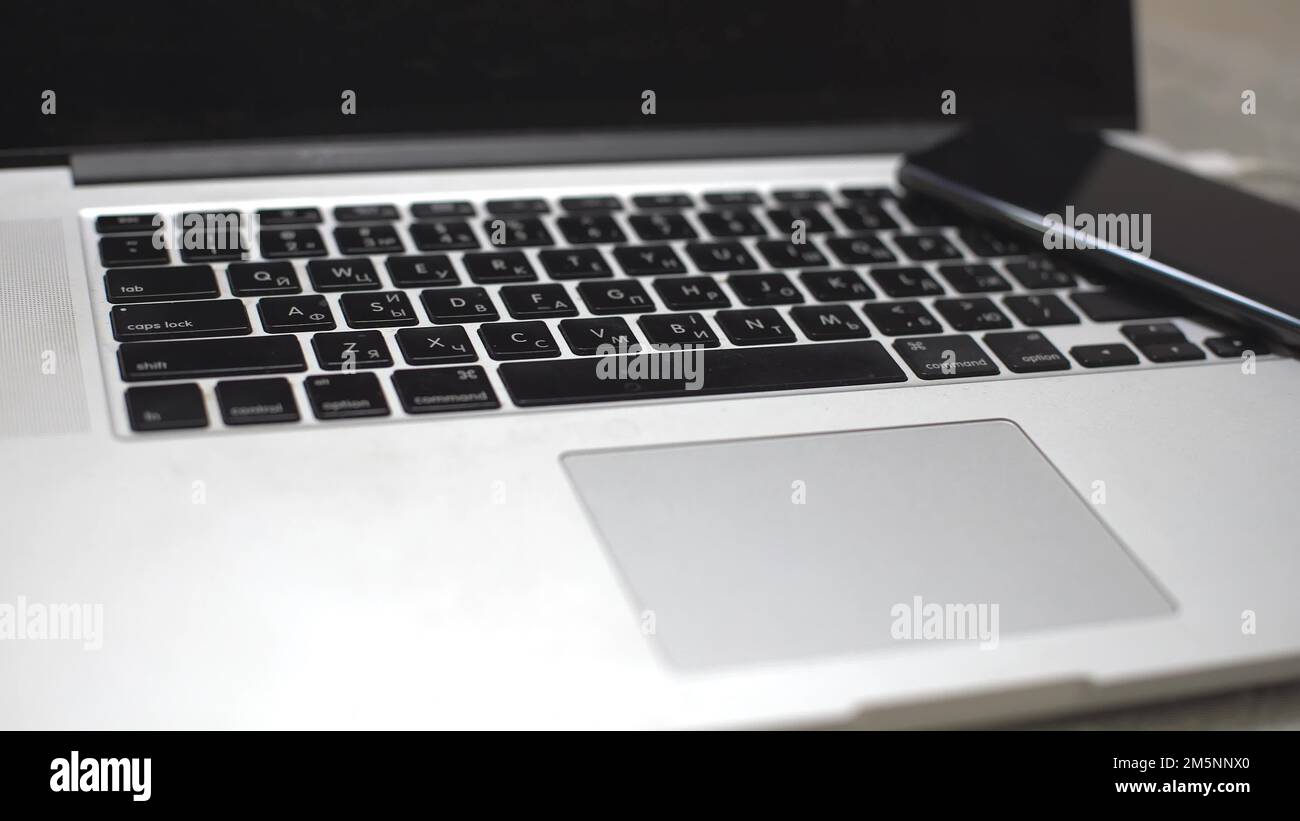 hand plugging the charger into cell phone against laptop computer Stock