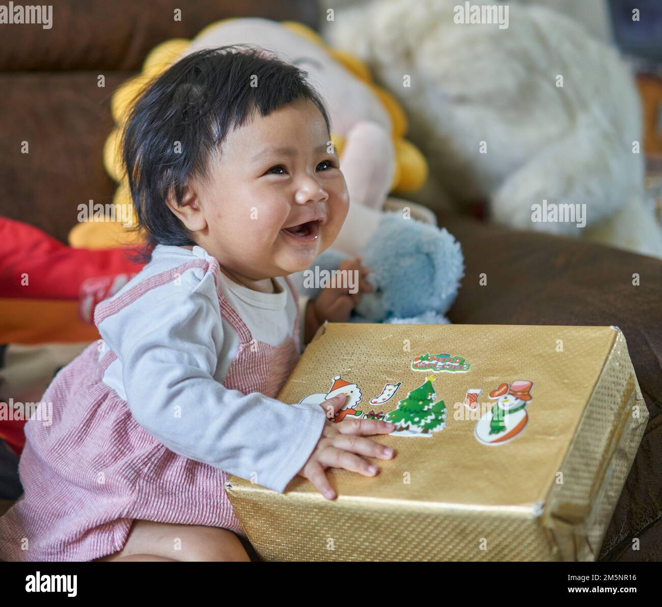 A small happy baby receives her first Christmas present. Stock Photo