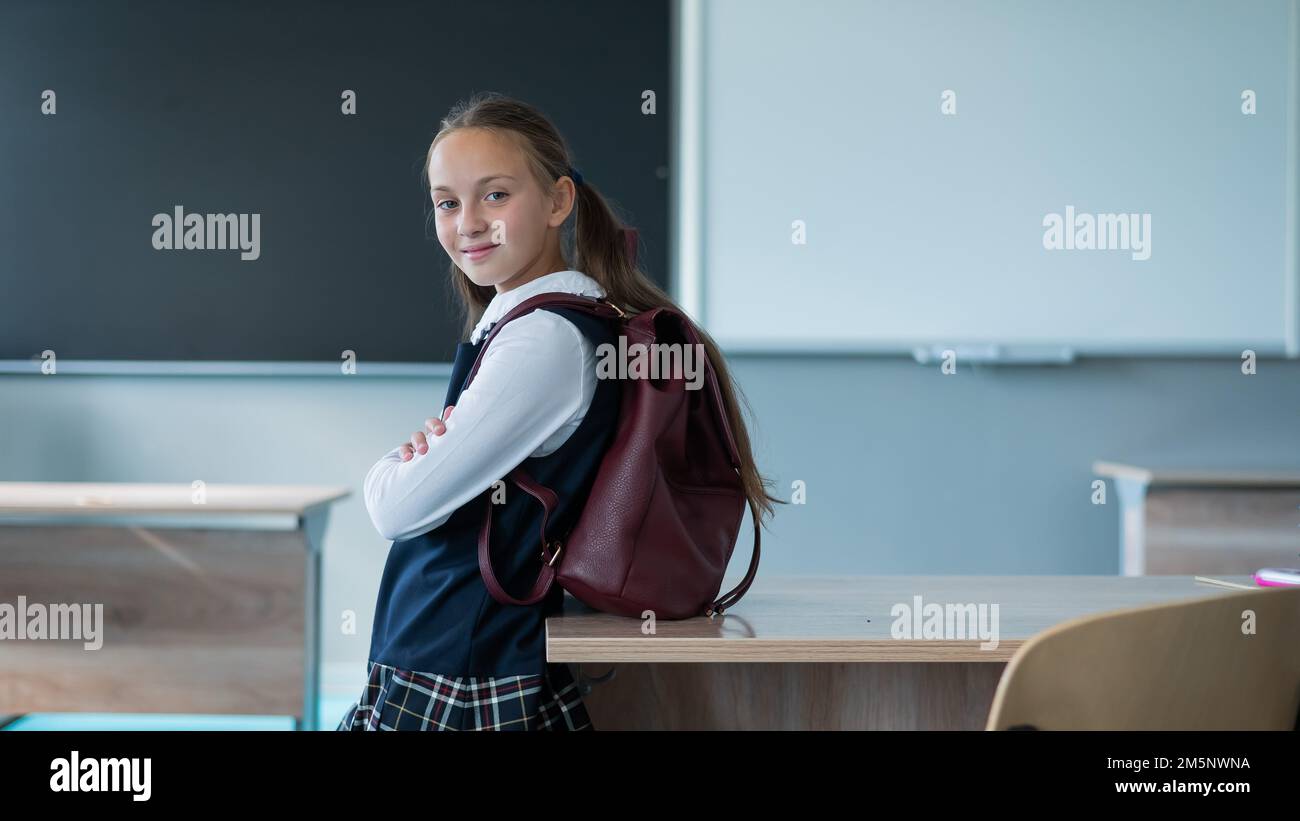 Portrait of a caucasian schoolgirl with a backpack in the classroom on ...