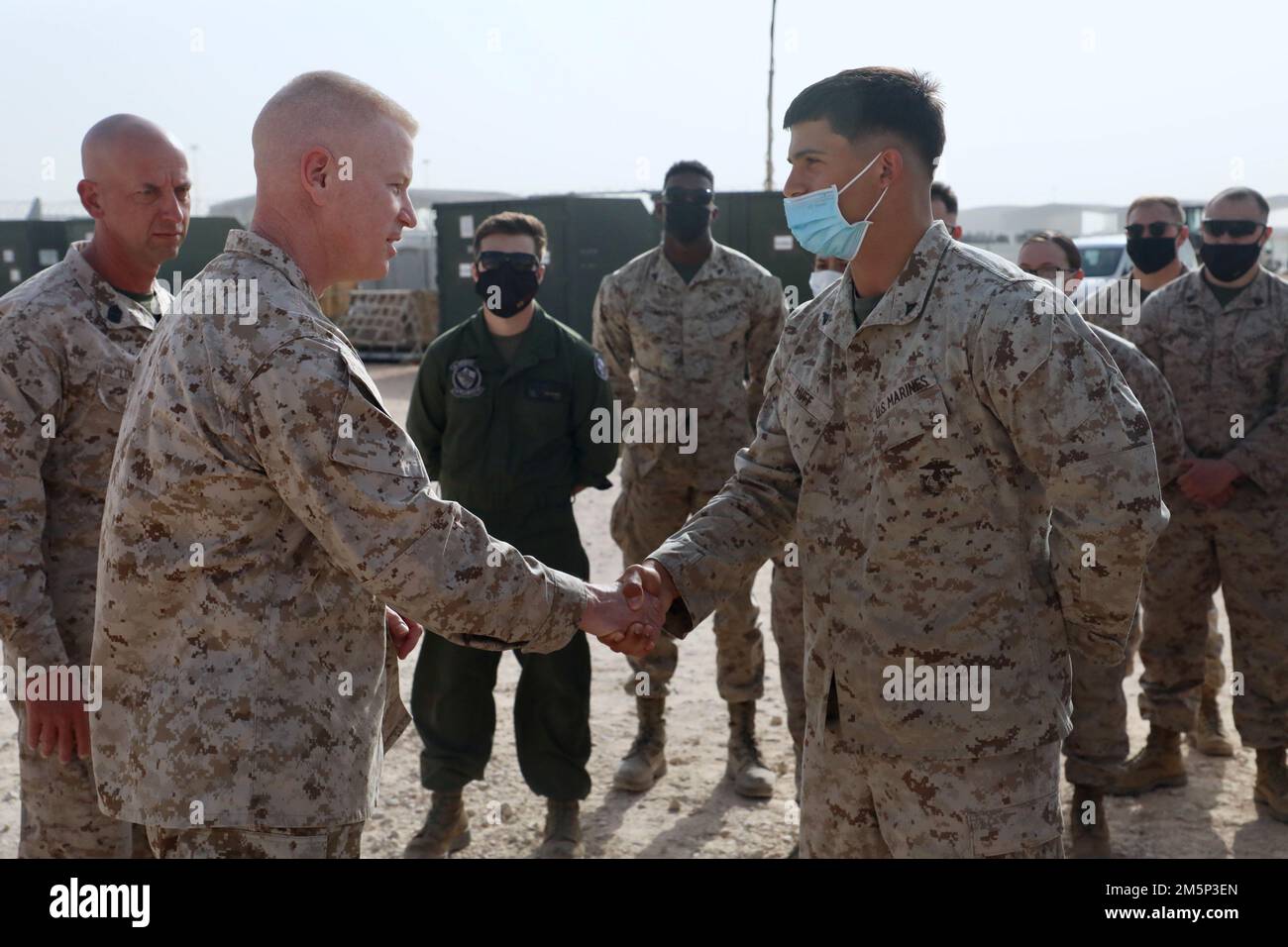 U.S. Marine Corps Maj. Gen. Paul Rock, Commander, U.S. Marine Corps Forces Central Command recognizes and presents his commander coin to Lance Cpl. Austin Huff, embark and logistics specialist, Marine Fighter Attack Squadron 115 (VMFA-115) for his hard work and performance while being deployed to Prince Sultan Air Base, Kingdom of Saudi Arabia, during his visit to Prince Sultan Air Base, Kingdom of Saudi Arabia on Feb. 27, 2022. VMFA-115 has been deployed to Prince Sultan Air Base in the Kingdom of Saudi Arabia since December 2021 and are an integral part of the Immediate Response Force in the Stock Photo